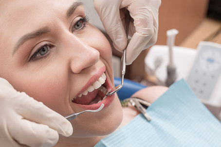 Close-up of female with open mouth during oral checkup at the dentist