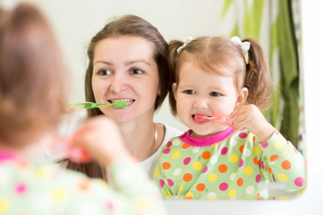 child and parent brushing teeth